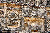 Uxmal - The Nunnery Quadrangle. The West building: frieze above the central door with the bodies of two  intertwined snakes, at left a medallion with a warrior in profile.