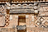 Uxmal - The Nunnery Quadrangle, the North Building. The frieze over the fifth doorway: a hut with two headed serpents above it and two jaguars with intertwined tails below.