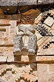 Uxmal - The Nunnery Quadrangle, the North Building. Stone figure of naked captive above the third and the fourth doorway.