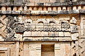 Uxmal - The Nunnery Quadrangle, the North Building. Detail of the frieze between the first and the second masks stack: traditional hut surmounted by three double-headed serpents. 