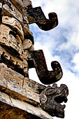 Uxmal - The Nunnery Quadrangle, the North Building. East end of the building masks stack of the N-E corner the 4 masks are almost identical showing unusual survival of snouts with curled upturned ends, serpent heads are at the bottom.