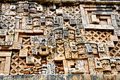 Uxmal - Palace of the Governor, front (East) facade. Frieze above 5th doorway from left, descending stair step of masks, note also the feathered headdress of a missing figure.