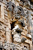 Uxmal - Palace of the Governor, front (East) facade. Frieze between 4th and 5th doorway from left representing a human figure with elaborate feathered headdress, seated on throne.