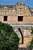 Uxmal - The great corbelled arch of the Nunnery with behind the masks stack (the third from left) of the North Building.