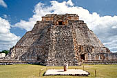 Uxmal - The west face of the  Magician Pyramid (el Adivino) seen from the Quadrangle of the Birds (Cuadrangulo de los Pajaros), with at the centre an altar and a column. 