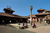 Bhaktapur - Tachupal Tole. Bhimsen Temple and the small temple dedicated to Vishnu. A brass statue of a lion stands on a pillar in front of the temple.