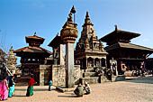 Bhaktapur - Durbar Square - Statue of Bhupatindra Malla King on top of a pillar, behind it the Taleju bell, Vatsala Durga temple, Chasilyn Mandapa (reconstructed) and on the right Pashupatinath temple. 