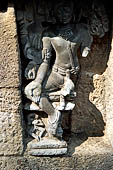 Hirapur - the Sixtyfour Yoginis Temple, weastern niche of the south wall of the mandapa, a ten armed figure with erected penis, with his leg he is pressing the head of a figure, in the pedestal a female attendant.