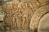 Udaigiri Cave 1  Rani Gumpha Queen's Cave - decorations of the three doorways of the veranda of the left wing of the ground floor. The first tableau (from left) represents a man, two women and a dwarf, one of the women carrying offerings. 