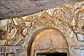 Udaigiri Cave 1 Rani Gumpha Queen's Cave - friezes of the upper storey. The story of a Kalinga queen carried away by Ashoka. First tableau: a man running with a tray in one hand. The large swastika is part of the following tableau.